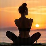 Frau in einer anmutigen Yoga-Pose, die Krieger-Position, am Strand bei Sonnenuntergang.